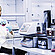 A lab technician prepares a sample next to an Anton Paar DMA 4500 M density meter with Xsample 530 sample changer and label printer.