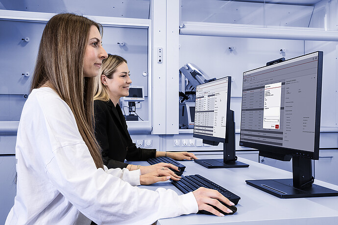 Two lab technicians use Anton Paar’s AP Connect software at desktop stations, with a DMA 4500 M density meter visible in the background.