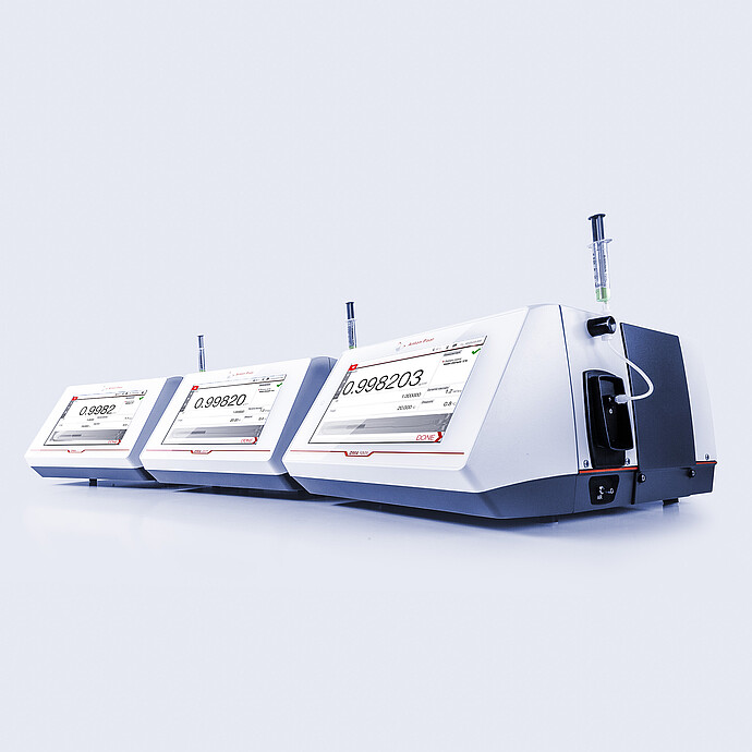 Three Anton Paar density meters — DMA 4101, DMA 4501, and DMA 5001 — arranged side by side in a studio setup with visible readings.