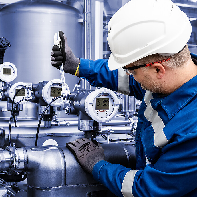 Technician using a wrench to install L-Cor 8500 Coriolis flow meter on industrial pipeline with multiple L-Cor 8500 transmitters and gauges